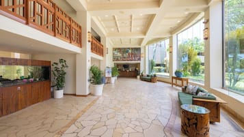 A spacious lobby with a large fish tank, potted plants, a reception desk, and a seating area with a view of the outdoors.