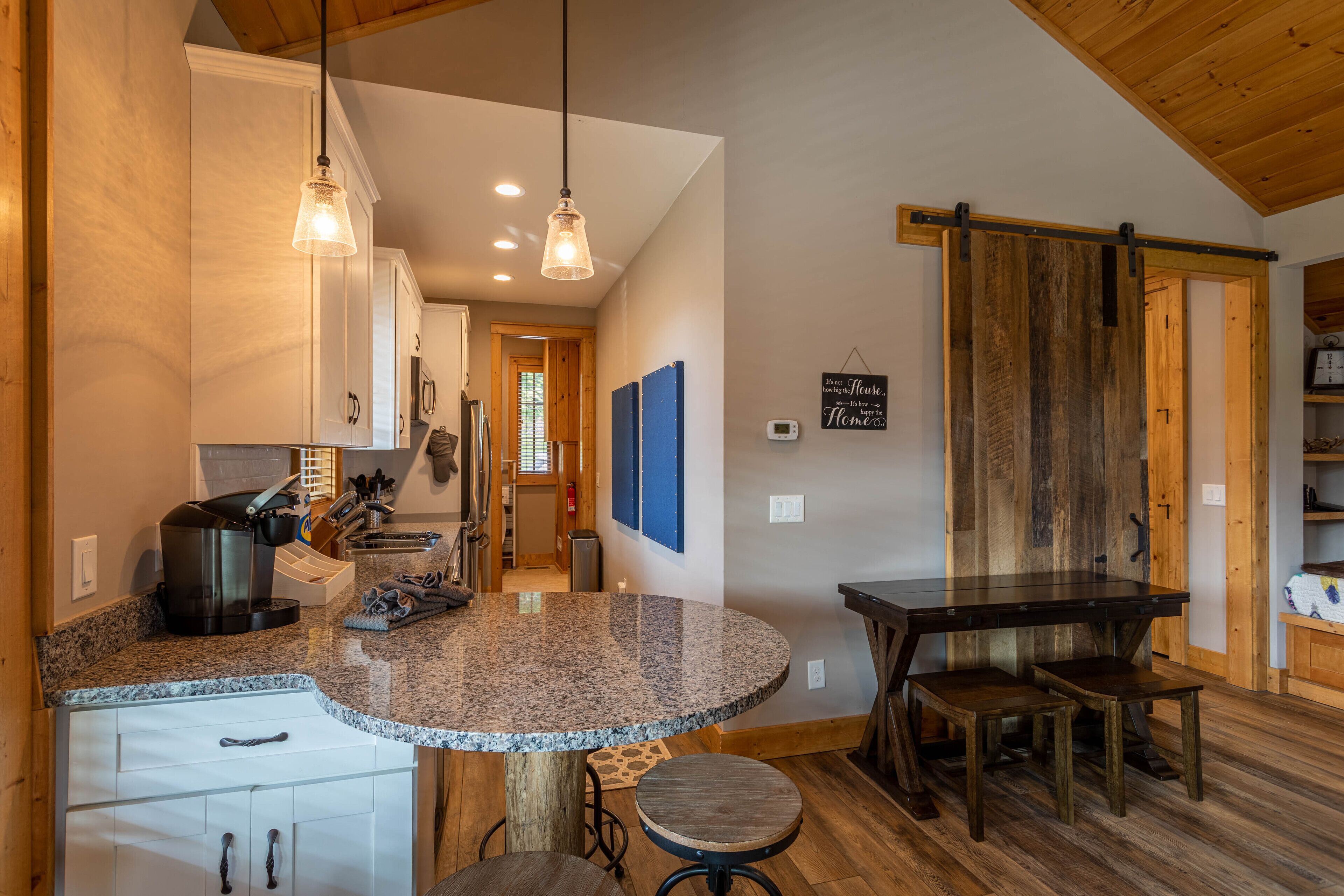 A kitchen with granite countertops, a coffee maker, and wooden flooring.