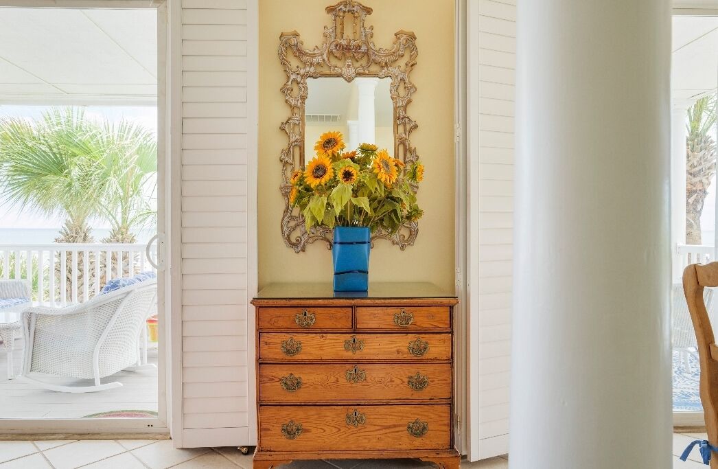 Une commode en bois avec un miroir et un vase bleu contenant des tournesols.