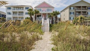 A beachfront hotel with a central building featuring a red roof, surrounded by two similar buildings. A sandy pathway leads to the entrance. - ☆Oceanfront Serenity☆ Private Pool & Beach Walkway (Myrtle Beach)