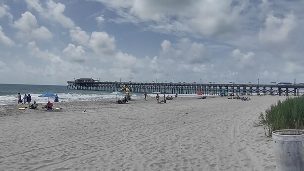 En strand med en mole, der strækker sig ud i vandet.
