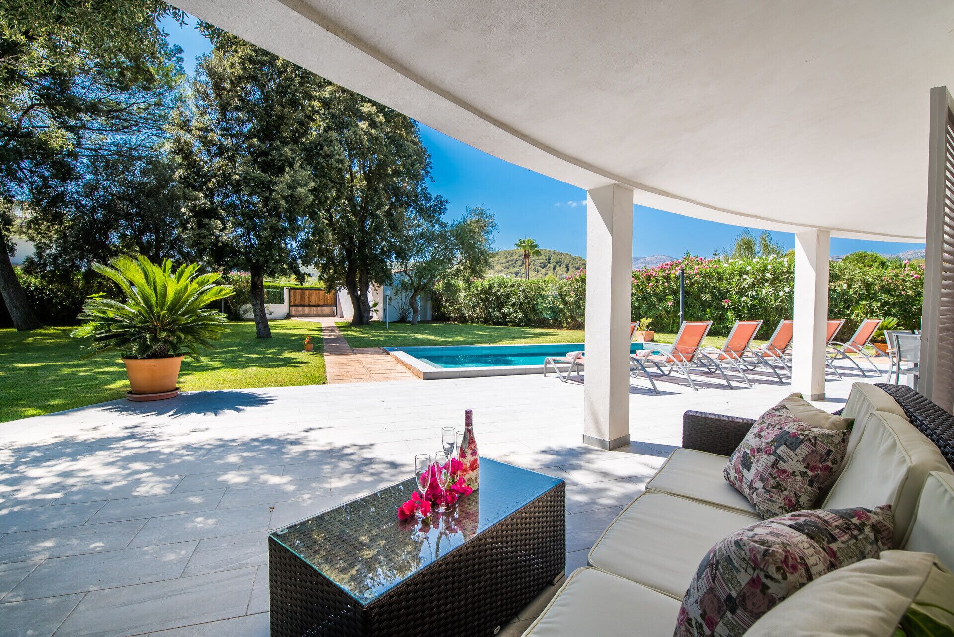 A covered outdoor area with a pool, lounge chairs, and a seating area with cushions.