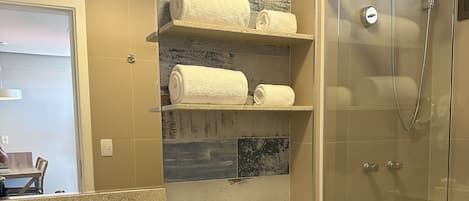 A modern bathroom with a glass-enclosed shower, a sink with a towel rack, and a toilet.