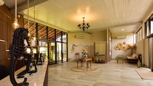 A spacious lobby with a reception desk, a chandelier, and a large window providing natural light. - Porto das Dunas Boutique Praia Hotel (Aquiraz)