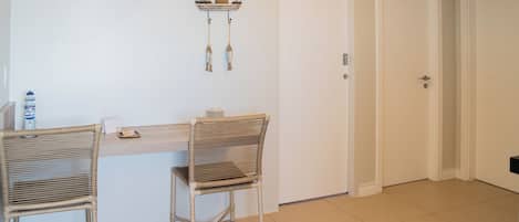 Un comedor con dos sillas de mimbre y una mesa de madera, una lámpara colgante y un adorno en la pared.