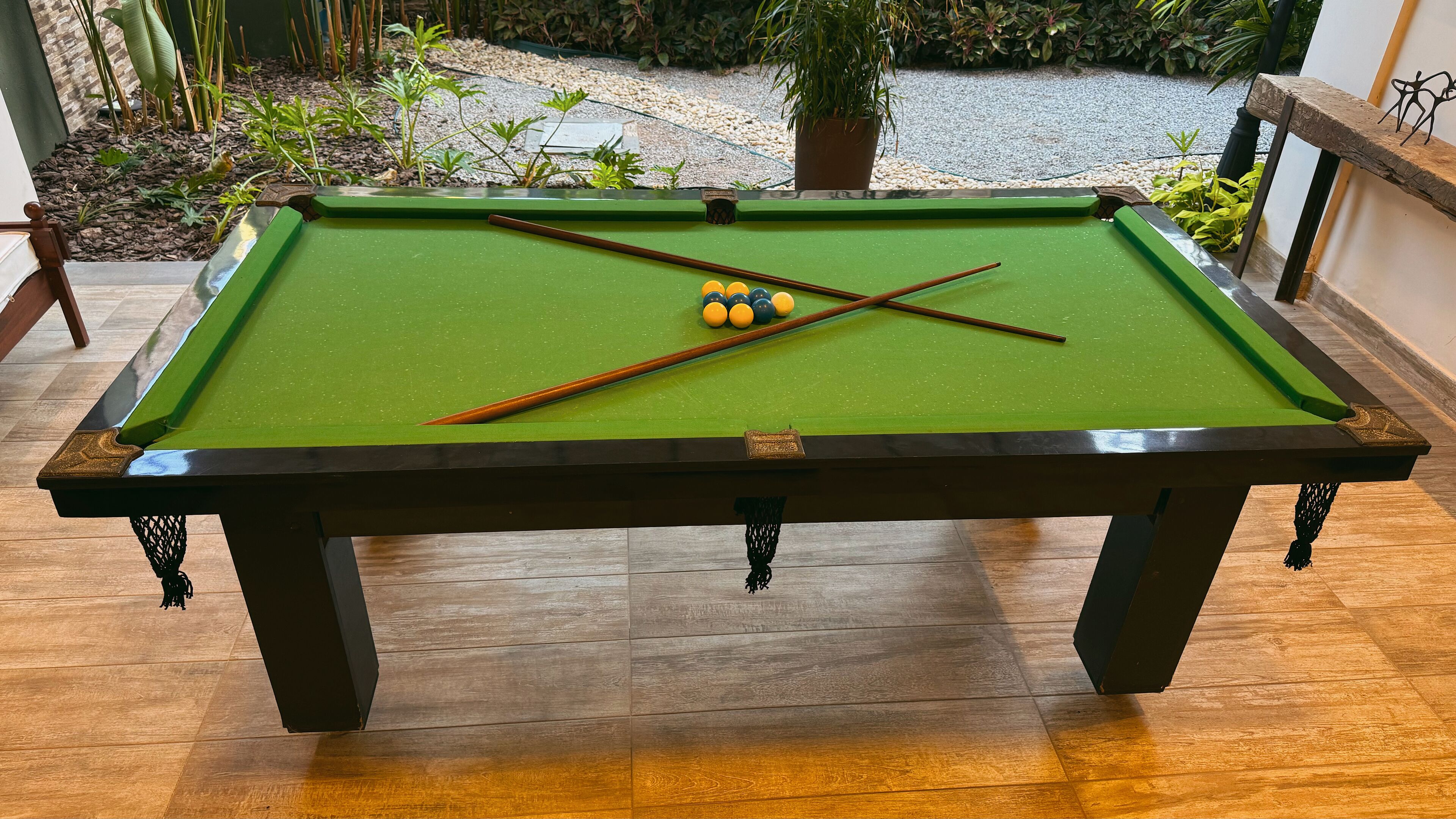 A pool table with a green felt surface, surrounded by a wooden floor.
