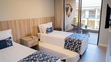 A hotel room with two beds, a small table, a chair, and a balcony with a view.
