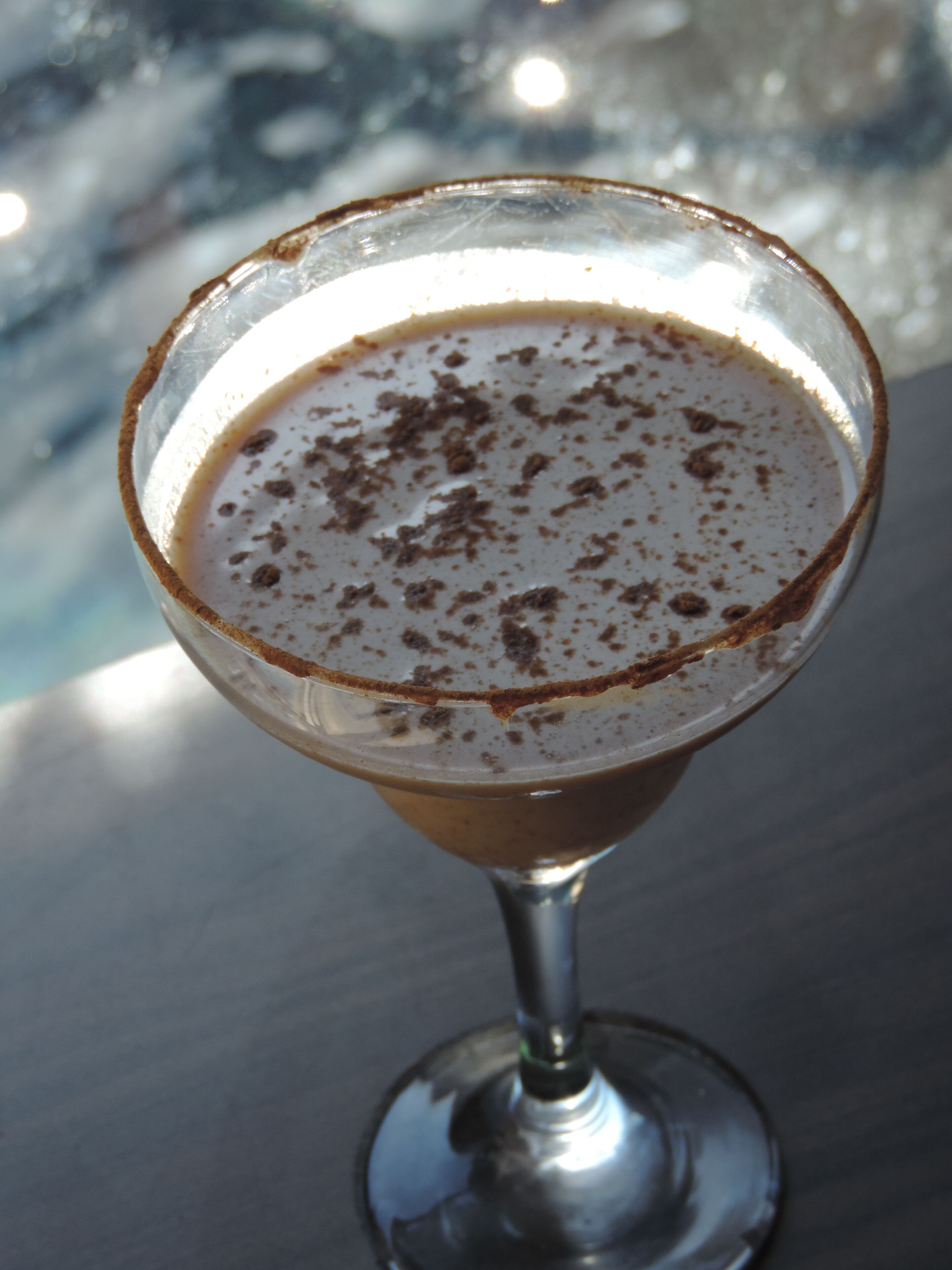 Un cóctel en una copa de martini, con el borde cubierto de virutas de chocolate.