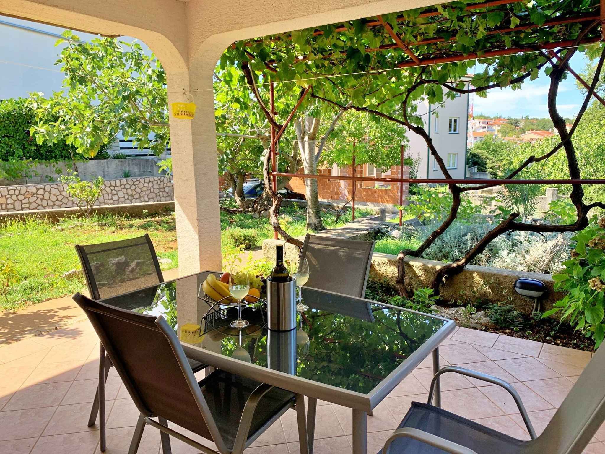 Terrassa exterior amb taula de vidre, cadires i una ampolla de vi.
