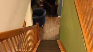 A staircase with carpeted steps leading to a room with a bookshelf and a blue chair. - Large, cozy vacation home in a quiet location (Groß Mohrdorf / Hohendorf)