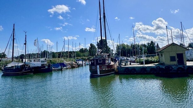 A marina with several sailboats docked, a small building, and a clear blue sky. - Large, cozy vacation home in a quiet location (Groß Mohrdorf / Hohendorf)