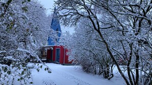 A snow-covered pathway leading to a red building with a blue tower in the background. - Large, cozy vacation home in a quiet location (Groß Mohrdorf / Hohendorf)