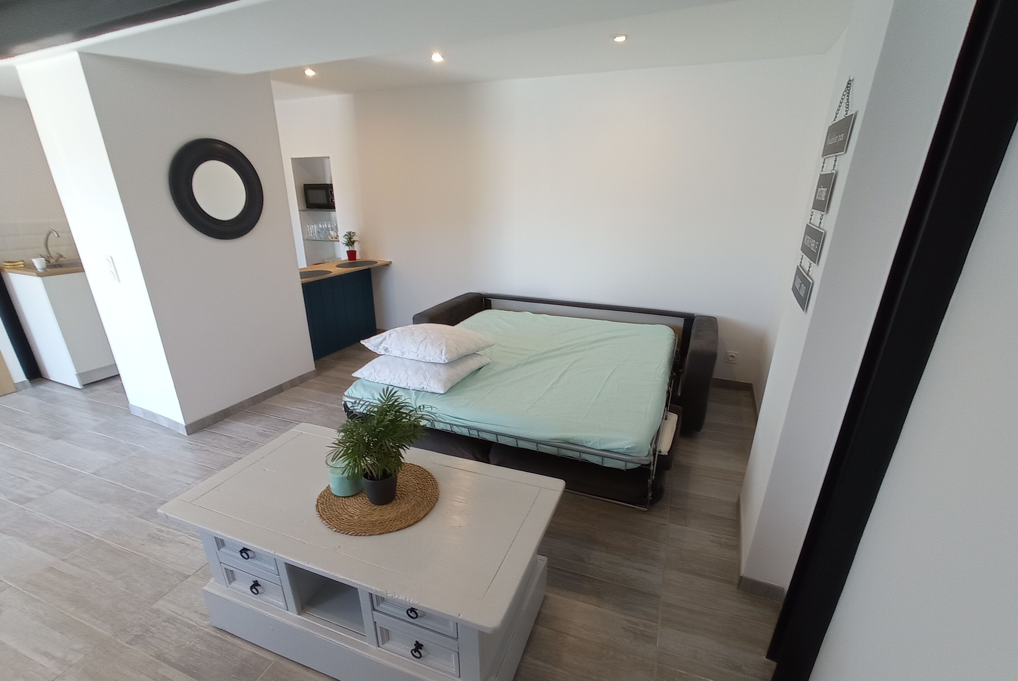 A modern bedroom with a bed, bedside table, and a small potted plant.