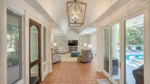 A spacious living room with a large TV, comfortable seating, and a view of a pool.