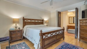 A bedroom with a wooden bed, two bedside tables with lamps, a chair, a dresser, and a mirror. - Sea Pines Home | Walk 2 Beach, Pool/Spa, Garage, Bikes (Hilton Head Island)