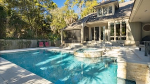 A swimming pool with a hot tub, surrounded by a covered patio with outdoor furniture.