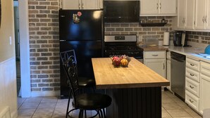 A kitchen with a central island, black chairs, a refrigerator, a microwave, and a dishwasher. - Charming house on Beautiful Doty Island (Neenah)