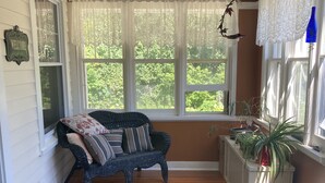 A cozy room with a wicker sofa, a patterned rug, and a view of greenery outside. - Charming house on Beautiful Doty Island (Neenah)