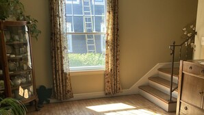 A room with wooden flooring, a window with curtains, a staircase, and a cabinet with glass doors. - Charming house on Beautiful Doty Island (Neenah)
