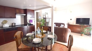 A modern kitchen with dark wooden cabinets, a glass dining table, and a comfortable seating area with a sofa and chairs. - Holiday apartment with sea view (Pinezići/Krk)