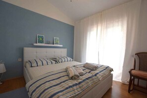 Une chambre à coucher avec un lit, une chaise, une table de chevet et une fenêtre avec des rideaux.