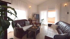 A living room with two leather sofas, a coffee table, a TV, and a potted plant. - Holiday apartment with sea view (Pinezići/Krk)