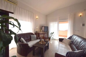 A living room with two leather sofas, a coffee table, a TV, and a potted plant. - Holiday apartment with sea view (Pinezići/Krk)