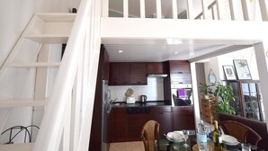 A modern kitchen with dark wooden cabinets, a stainless steel range hood, and a dining area with wicker chairs and a glass table. - Holiday apartment with sea view (Pinezići/Krk)