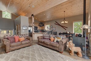 Een ruime woonkamer met twee leren banken, een groot tapijt en een decoratief hondenbeeld.