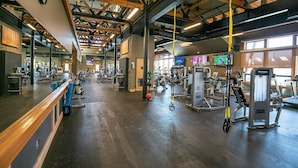 A spacious gym with various exercise equipment, wooden beams on the ceiling, and large windows allowing natural light. - Treetop at Tahoe Donner By Tahoe Getaways - Dog OK - Access to Gym, Pool, Beach (Truckee)