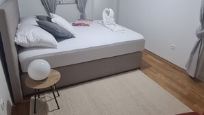 Une chambre à coucher avec un lit, une chaise rouge, une lampe blanche et une fenêtre avec des rideaux.