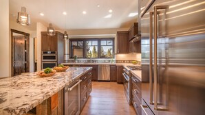 A modern kitchen with a large island, stainless steel appliances, and wooden cabinetry.