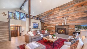 A spacious living room with a fireplace, a sofa set, a coffee table, and a red patterned rug.