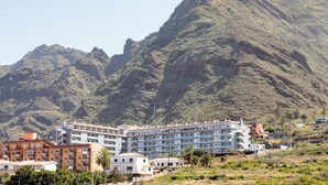 Un hôtel à plusieurs étages, doté d’un toit plat et de balcons, et entouré d’un paysage montagneux.