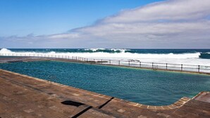 Une piscine avec vue sur l’océan, où l’on peut admirer les vagues qui se brisent sur le rivage.