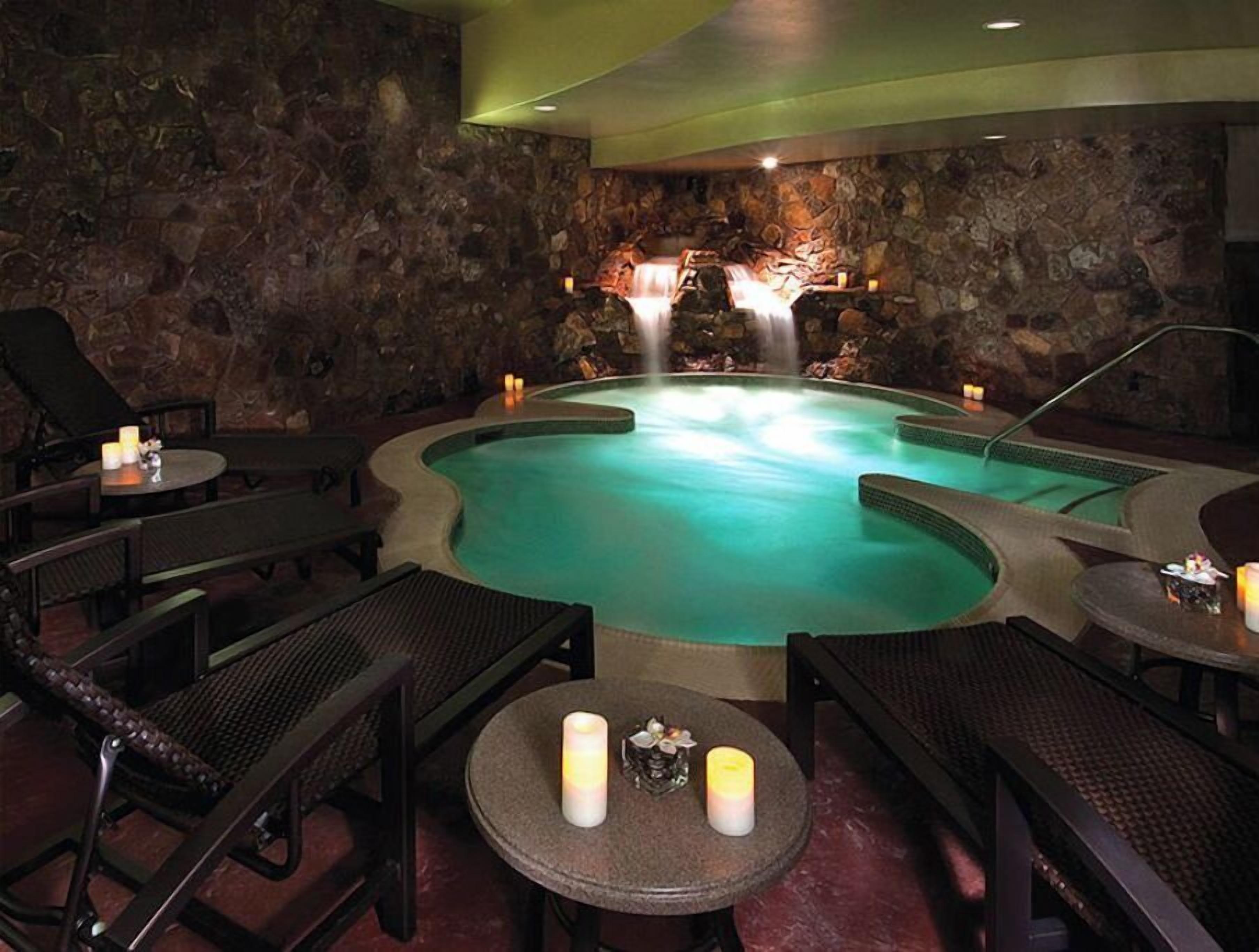 A spa area with a hot tub, stone walls, and seating.
