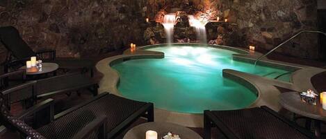 A spa area with a hot tub, stone walls, and seating.