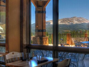 A restaurant with a mountain view, featuring a stone pillar, wooden tables, and metal chairs. - Ski in Ski Out Luxury Resort  (Breckenridge)