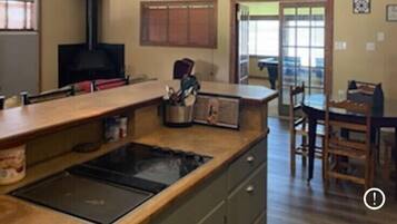 A kitchen with a central island, a stove, and a ceiling fan. There is a dining area with a table and chairs.
