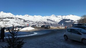 A parking area with snow-covered mountains in the background. - Apartment at the foot of the slopes in a typical village of our mountains (Les Coches, La Plagne-Tarentaise, France)