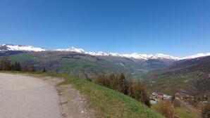 A mountain landscape with snow-capped peaks and a valley below. - Apartment at the foot of the slopes in a typical village of our mountains (Les Coches, La Plagne-Tarentaise, France)