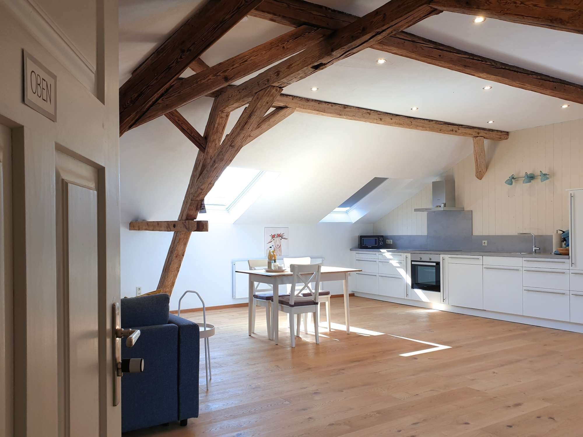 A modern kitchen with white cabinets, a built-in oven, and a skylight.