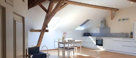 A modern kitchen with white cabinets, a built-in oven, and a skylight.