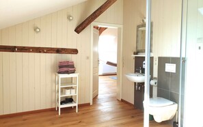 Un pasillo estrecho que conduce a un baño con lavamanos y retrete blancos.