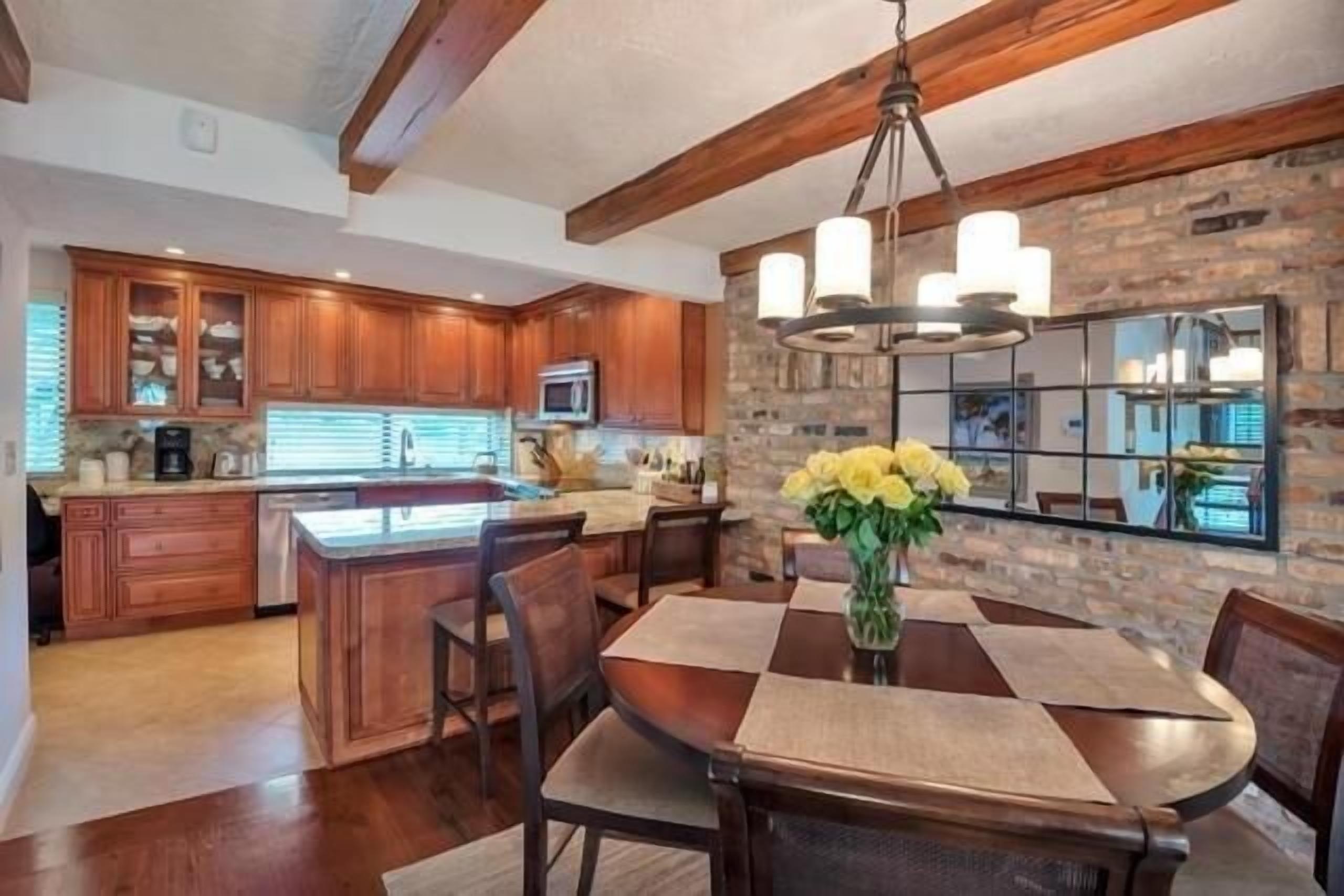 A spacious kitchen with wooden cabinets, a central island, and a dining area with a table and chairs.