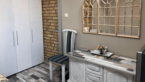 A small, modern kitchen with a white cabinet, a striped chair, and a decorative mirror on the wall. - Very nice luxury apartament (Varna)