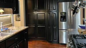 A modern kitchen with dark cabinetry, stainless steel appliances, and a granite countertop.