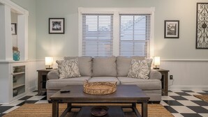 A living room with a sofa, two side tables, a coffee table, and a checkered floor.