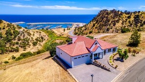 Una proprietà costiera con un edificio a tetti rossi, una marina piena di barche e un paesaggio collinare.