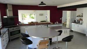 Cozinha moderna com ilha central, banquetas e vista para o exterior.